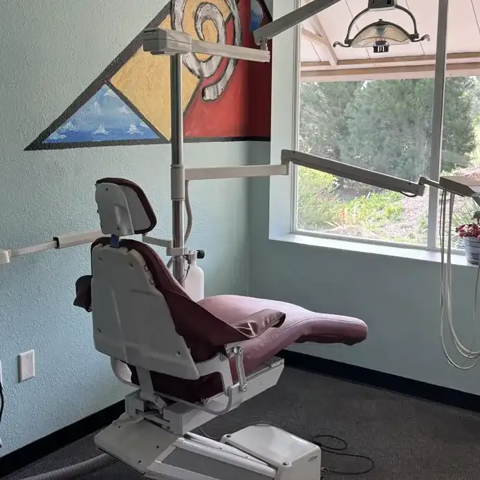 Dental treatment chair in a dental operatory with overhead lights and window view outside